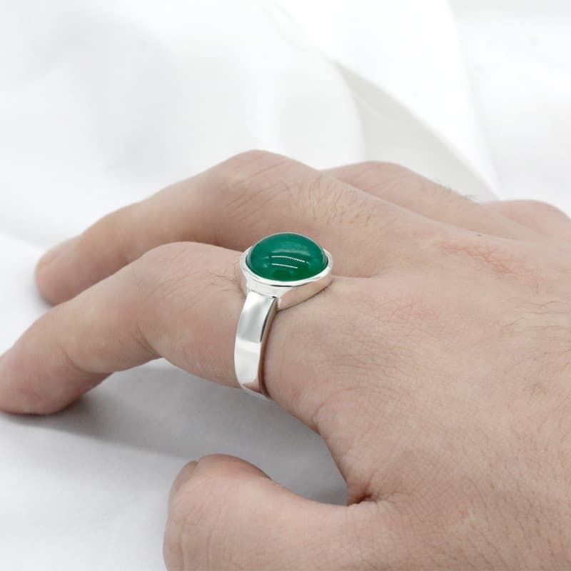 Der Mann hat einen Ring mit einem grünen Stein am Zeigefinger.