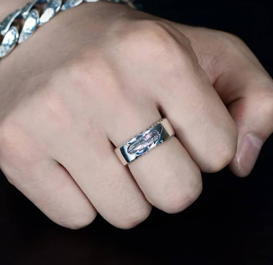 Der Mann hat einen silbernen Ring mit Feder Muster am Mittelfinger