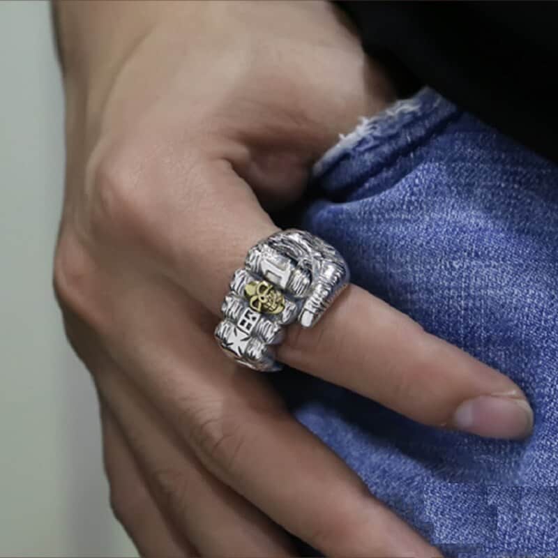 Am Zeigefinger trägt er einen faust förmigen Ring.
