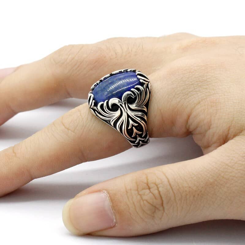 Der Mensch trägt einen großen blauen Stein-Silberring an seinem Zeigefinger