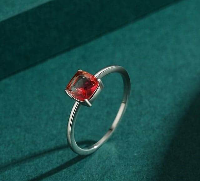 Silber Ring mit rotem Stein auf grünem Hintergrund