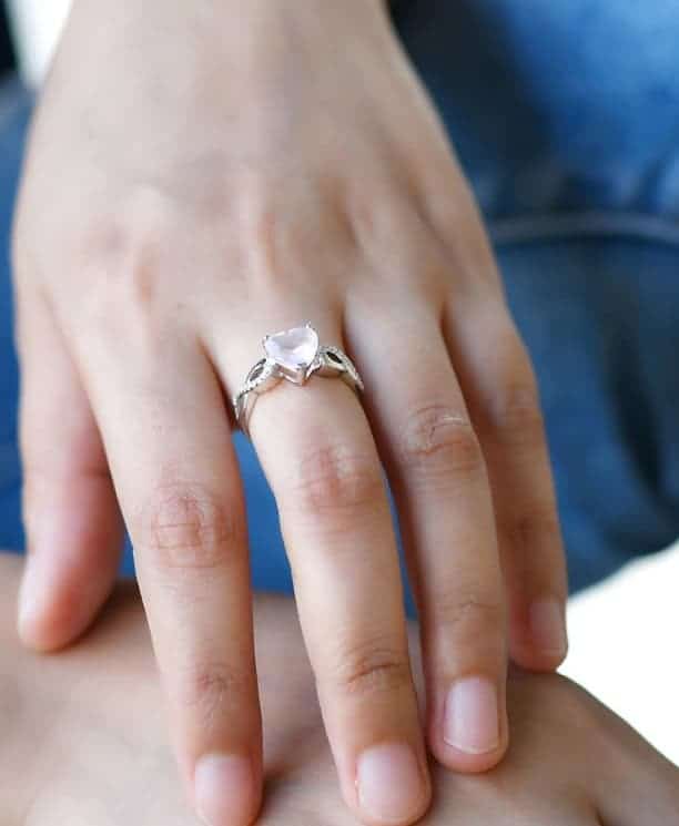 Frau hat einen rosa Herz-Silberring an ihrem Mittelfinger