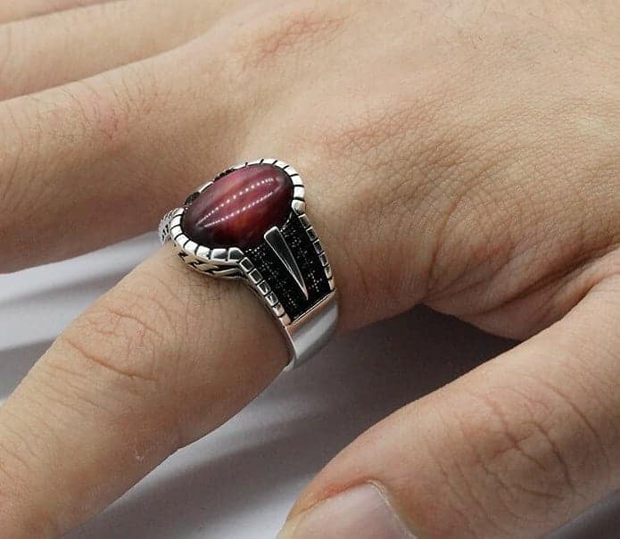 Mann hat einen silbernen Ring mit rotem Stein auf seinem Zeigefinger