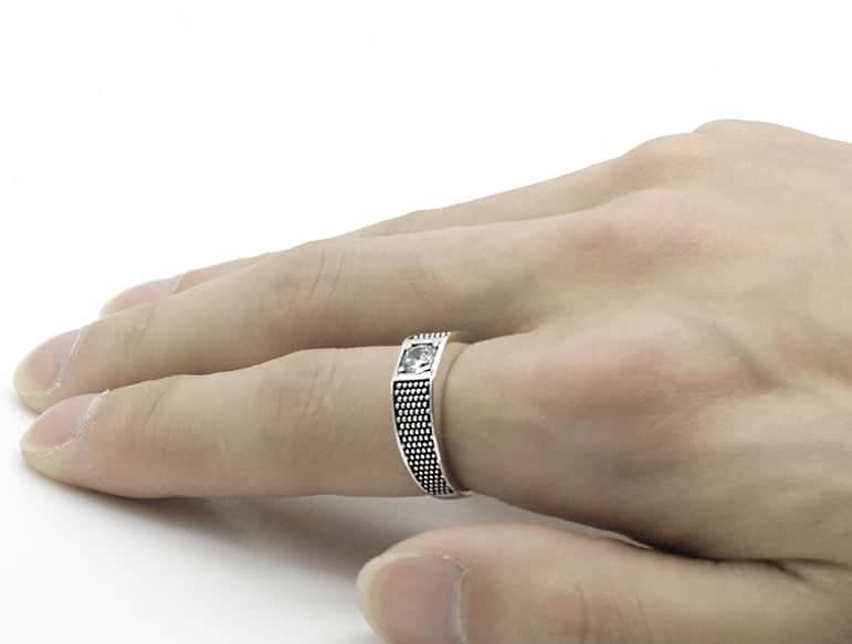 Mann hat einen silbernen Ring mit Zirkonstein auf seinem Zeigefinger