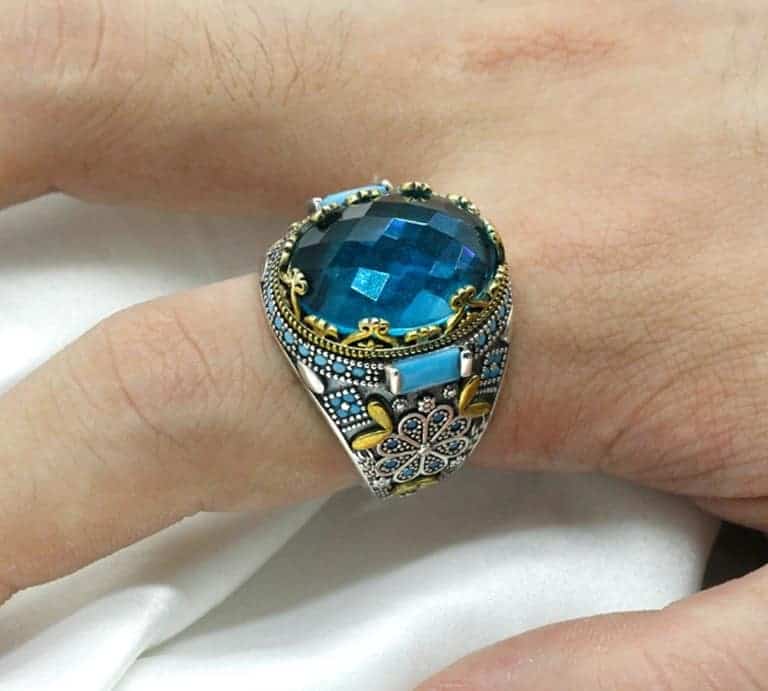 Der Mann hat einen Silber Ring mit einem blauen Stein am Zeigefinger