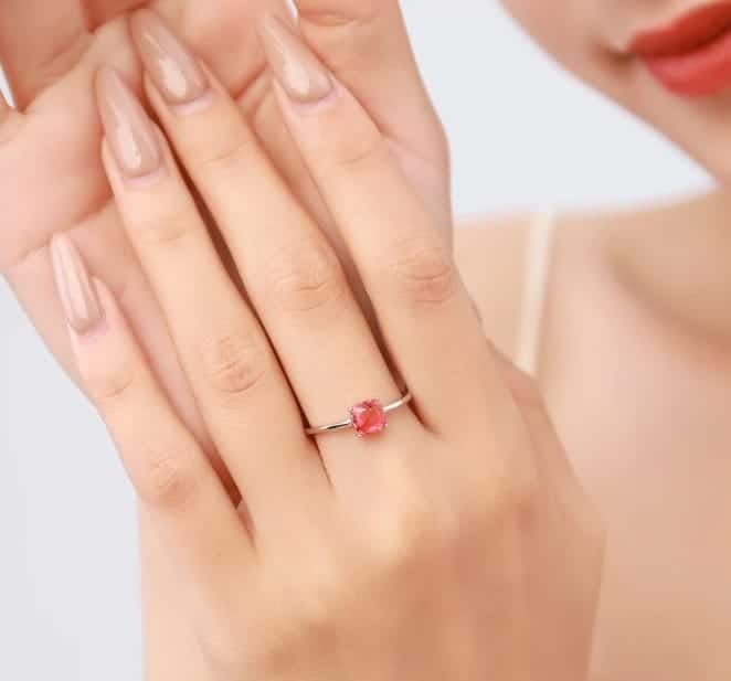 Die Frau hat einen Silber Ring mit einem roten Stein am Mittelfinger