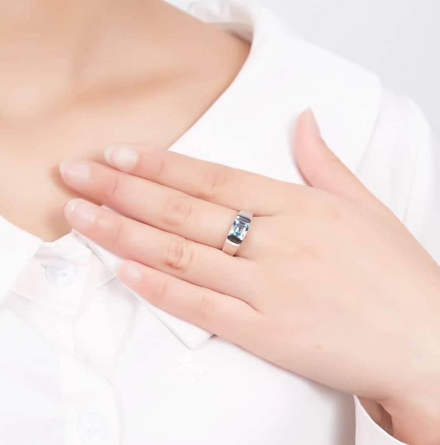 Die Frau hat einen silbernen Ring mit einem blauen Stein am Mittelfinger
