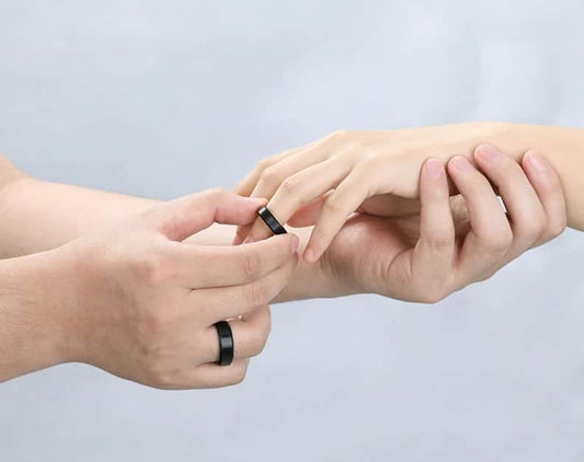 Der Mann trägt einen Ehering schwarz am Finger der Frau.