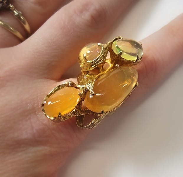 Frau hat einen orangefarbenen Opal Ring an ihrem Finger