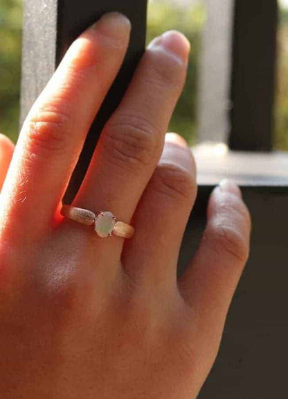 Frau hat einen Opal Ring an ihrem Mittelfinger