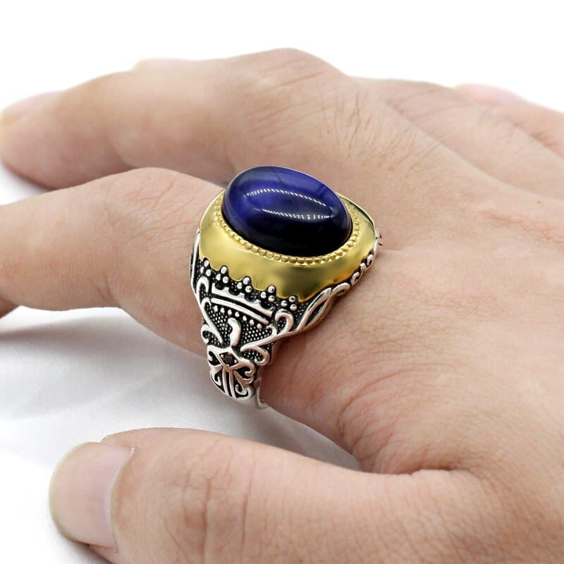 Der Mann trägt einen silbernen Ring mit blauem Tigerauge-Stein am Zeigefinger