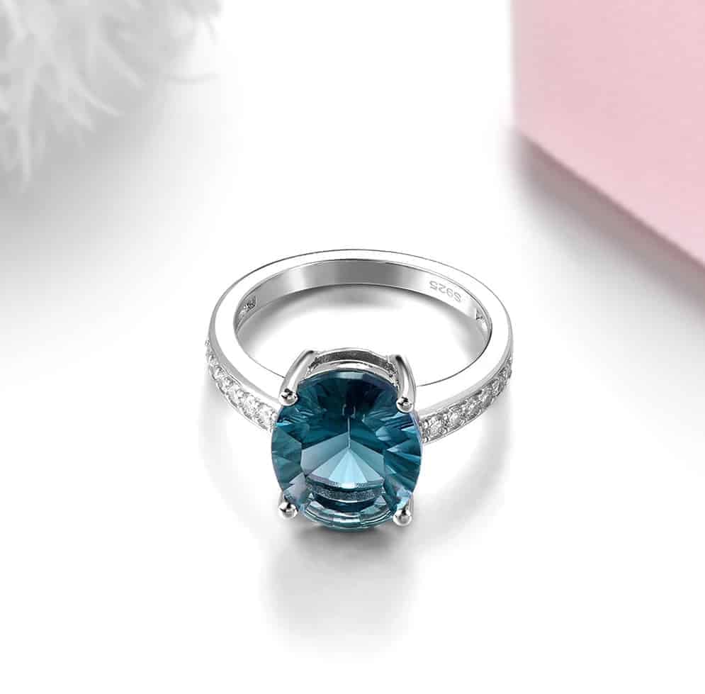 Auf dem Tisch liegt ein silber Ring mit einem blauen Stein