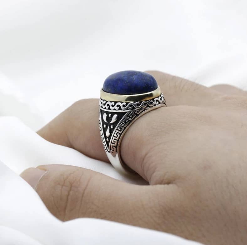 Der Mann hat einen Ring mit einem blauen Stein am Finger