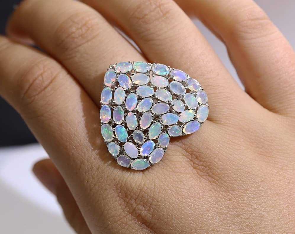 Frau trägt einen weißen Opal stein ring an ihrem Mittelfinger