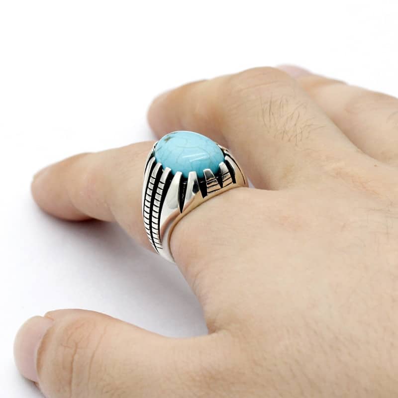 Der Mann trägt einen silbernen Ring mit einem türkisfarbenen Stein am Zeigefinger