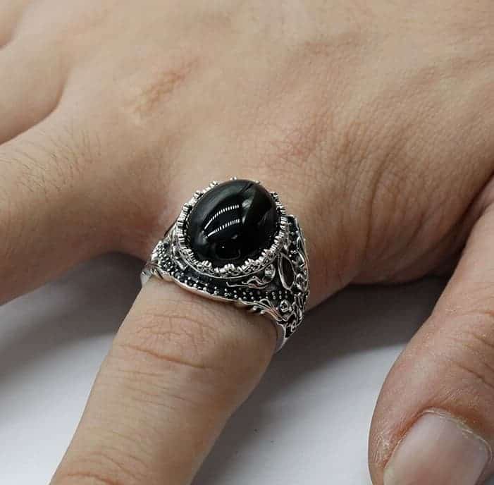 Mann hat einen silbernen Ring mit schwarzem Stein auf seinem Zeigefinger