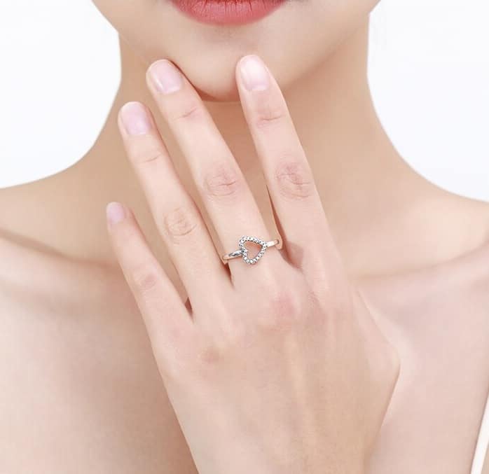 Frau hat einen Herz Ring an ihrem Mittelfinger