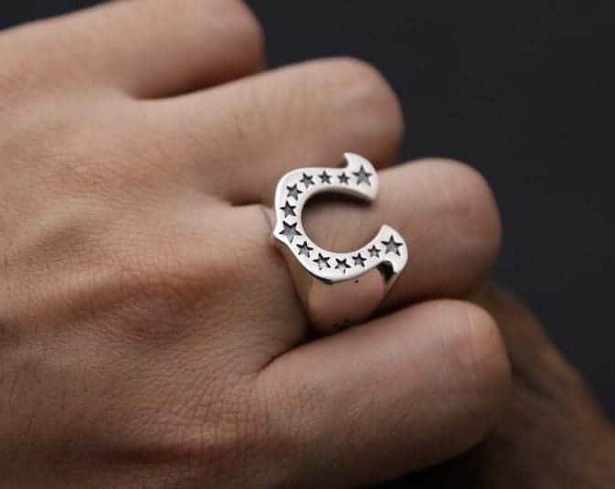 Der Mensch hat einen silber Ring mit Hufeisenmuster an seinem Mittelfinger