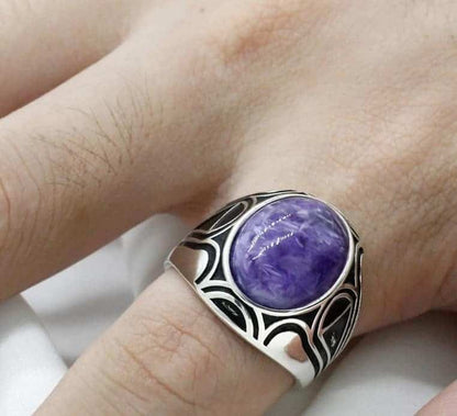 Der Mann hat einen 925er Silber Ring mit einem violetten Stein an seinem kleinen Finger