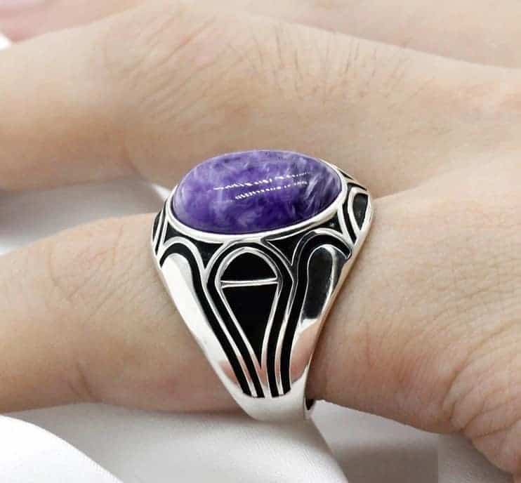 Der Mann hat einen silbernen Ring mit einem violetten Stein an seinem kleinen Finger