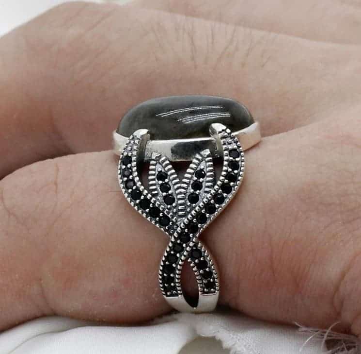 Der Mann hat einen Mondstein Ring mit schwarzem Zirkonia am Zeigefinger.