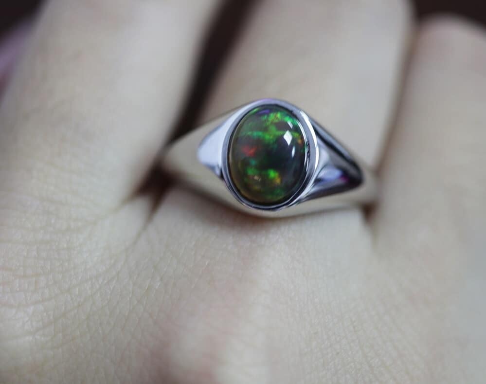 Die Frau trägt einen Opal ring mit einem grünen Stein am Finger.