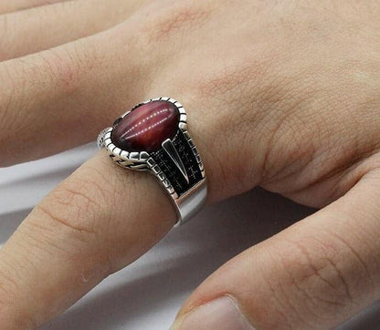 Mann hat einen silbernen Ring mit rotem Stein auf seinem Zeigefinger