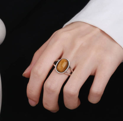 Die Frau hat einen silbernen Ring mit einem gelben ovalen Stein am Mittelfinger