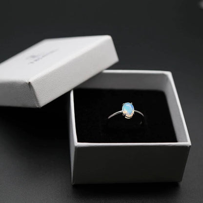 In der Box befindet sich ein silberner Ring mit einem weißen Opalstein.