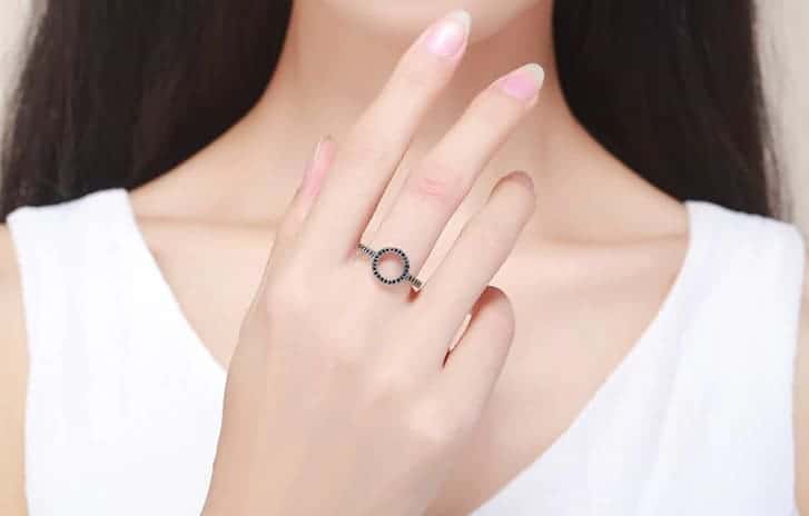 Die Frau hat einen silbernen Ring mit schwarzem Zirkonia am Mittelfinger